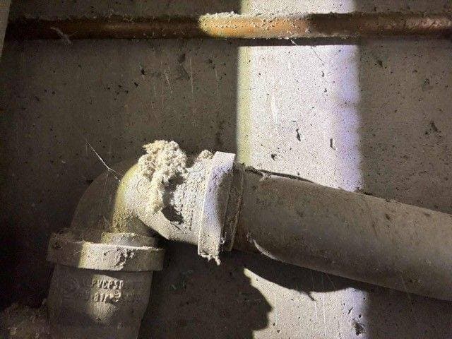 Nagromadzony osad w kolanku Kolanko starej rury pokazujące nagromadzony osad blokujący przepływ