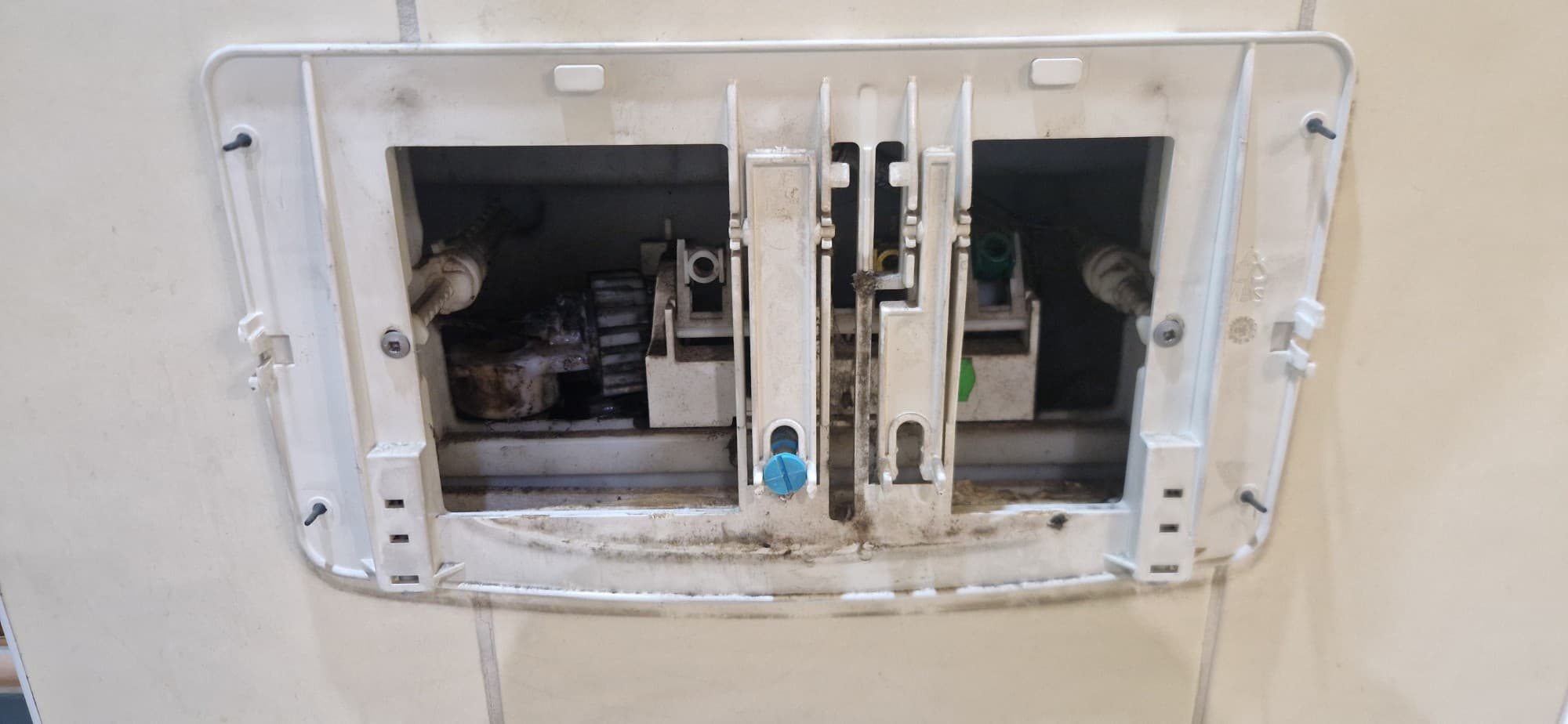 Mechanizm przed naprawą Wnętrze mechanizmu spłuczkowego przed naprawą z widocznymi uszkodzeniami