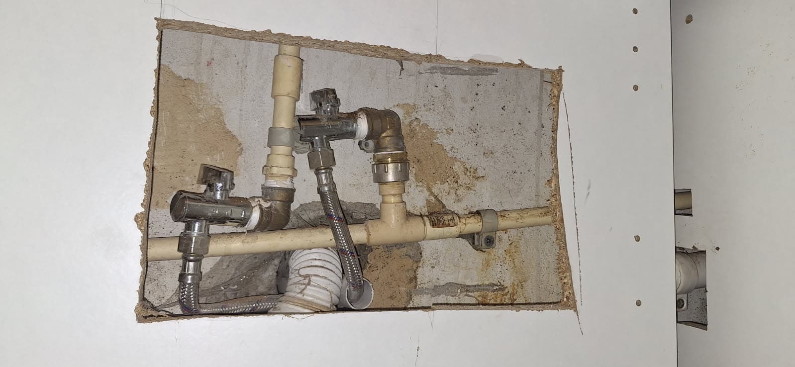 Naprawiona instalacja wodna Miejsce naprawy rury pod szafką kuchenną z nowymi połączeniami