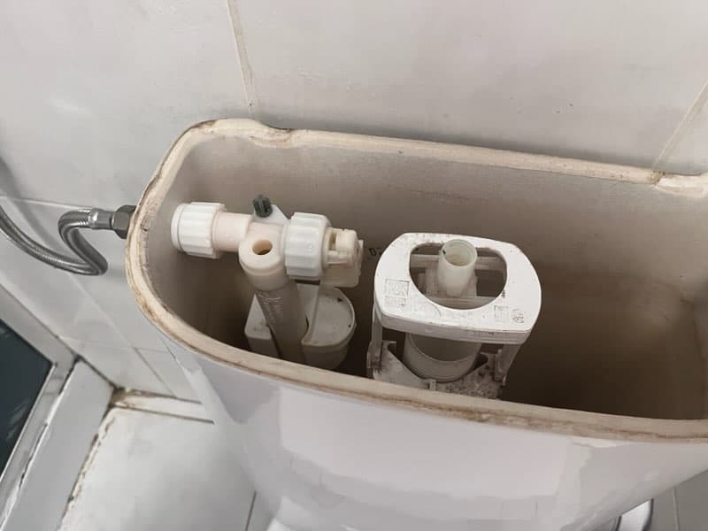 Mechanizm spustowy przed wymianą Wnętrze zbiornika toalety z widocznym mechanizmem spustowym