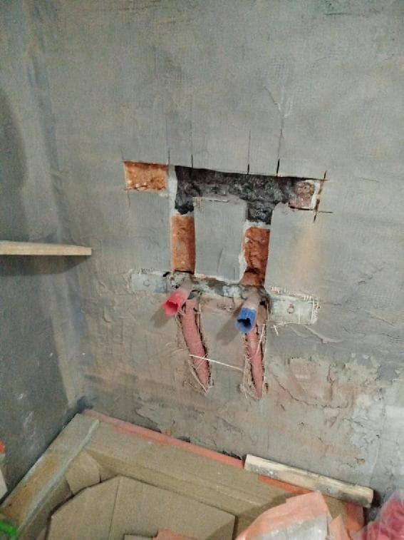 Przygotowanie rur plastikowych do przedłużenia Otwór w ścianie z widocznymi rurami plastikowymi przygotowanymi do przedłużenia.