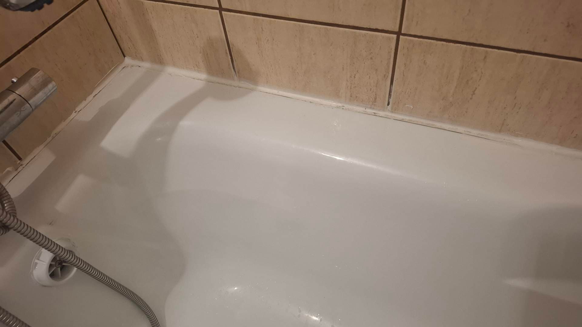 Detail narożnika z silikonem Zbliżenie na narożnik wanny pokazujące starannie położony nowy silikon.
