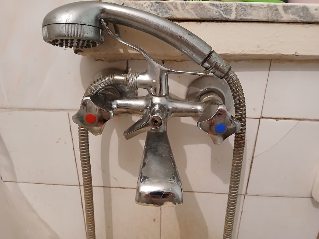 Stara bateria prysznicowa Stara bateria prysznicowa zamontowana nad wanną z widocznym osadem