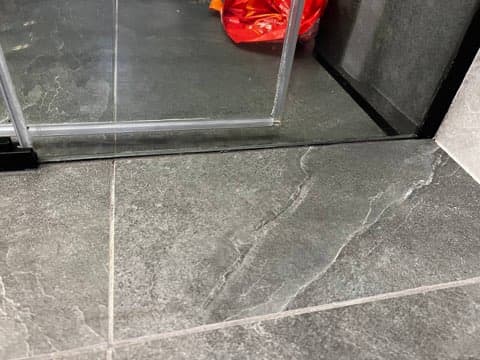 Nowe uszczelnienie narożnika Nowo nałożony ciemnoszary silikon w narożniku kabiny prysznicowej.