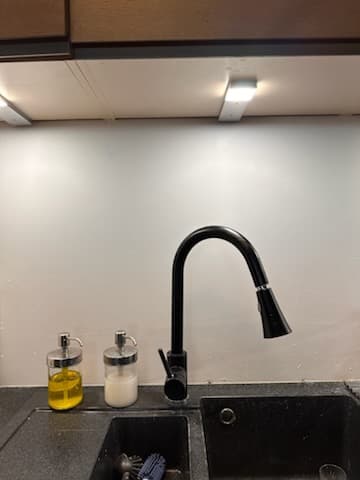 Czarna bateria kuchenna Czarna bateria kuchenna z wyciąganą funkcją spłukiwania nad czarnym blatem