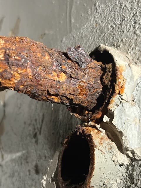 Skorodowana rura przy ścianie Detal skorodowanej rury metalowej wychodzącej ze ściany