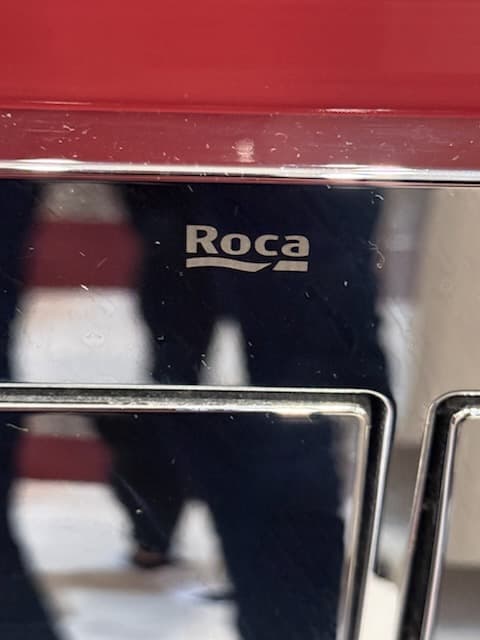 Przycisk spłukujący Roca Zbliżenie przycisku spłukującego marki Roca na ścianie łazienkowej