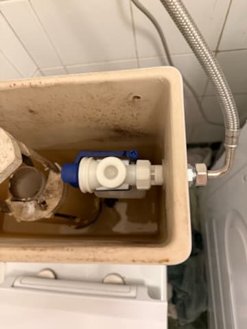 Stan spłuczki przed naprawą Nieszczelna spłuczka WC przed naprawą, widoczne uszkodzone elementy