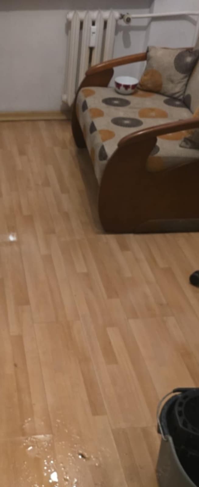 Woda na podłodze przy kanapie Fragment pomieszczenia z widocznym wyciekiem wody blisko kanapy