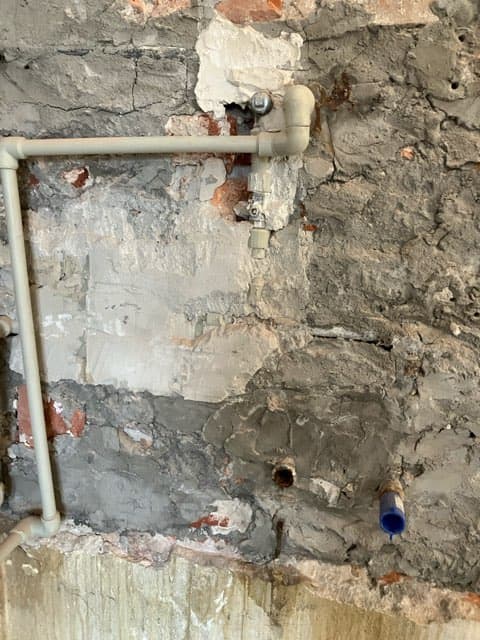 Instalacja wodna przed naprawą Ściana z widoczną instalacją wodną przed naprawą
