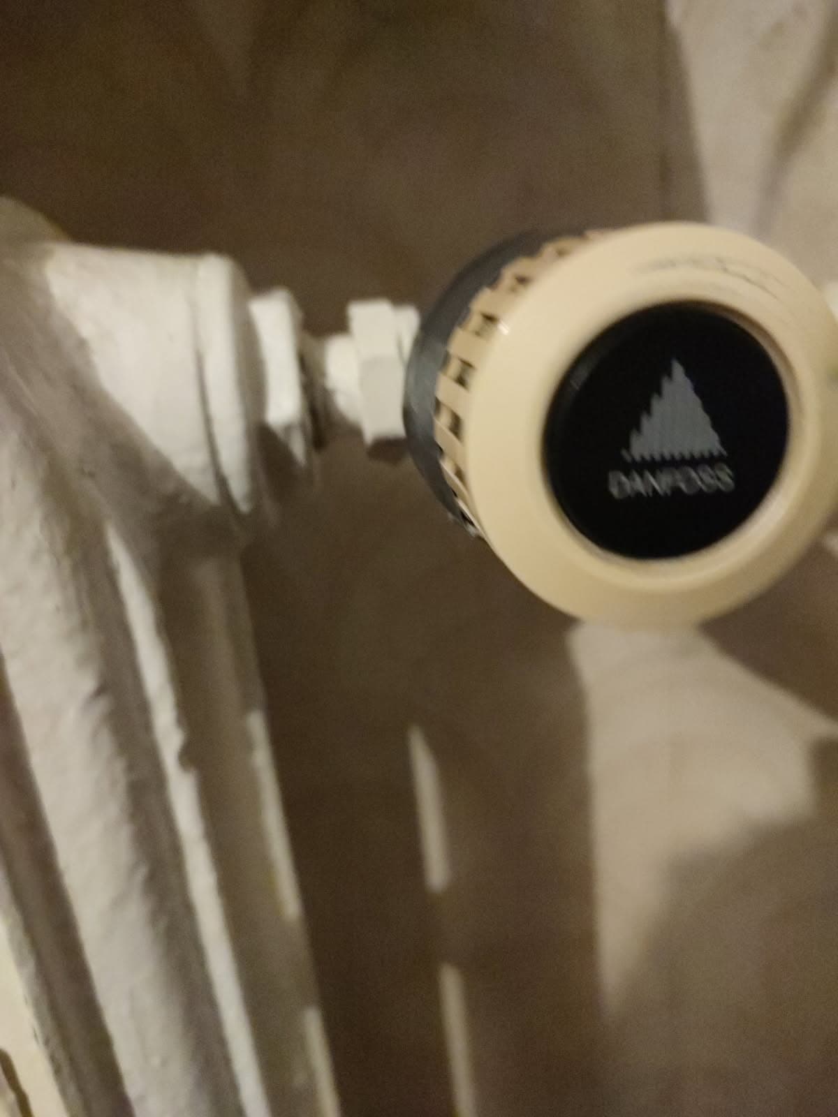 Pokrętło Danfoss na żeliwnym grzejniku Pokrętło termostatyczne Danfoss zamontowane na białym żeliwnym grzejniku