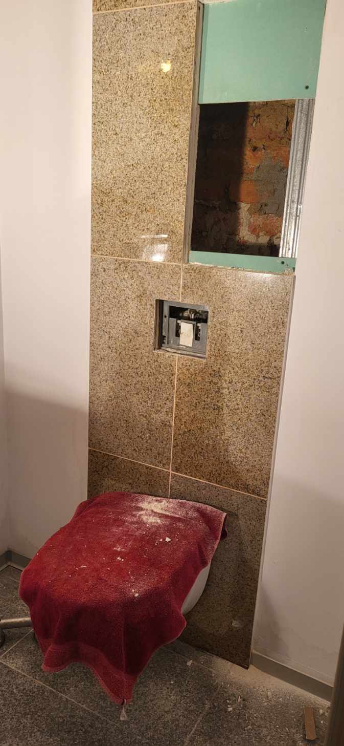 Zabudowa granitowa przed naprawą Odsłonięta zabudowa granitowa przed naprawą instalacji wodnej w firmie.