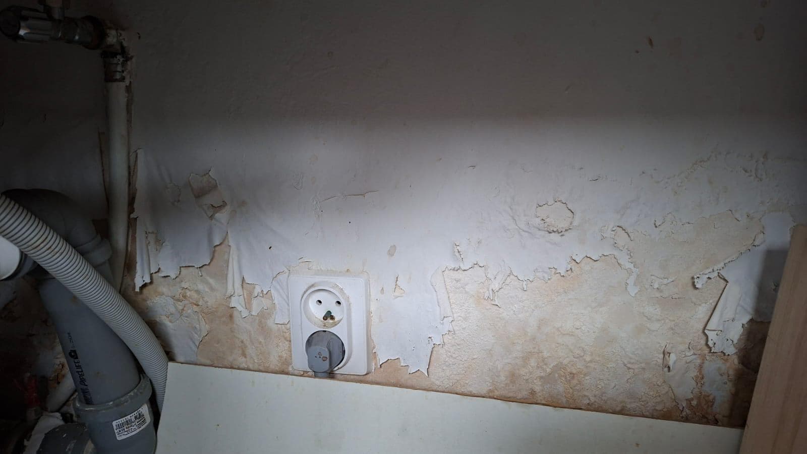 Ściana z wilgocią i rurą odpływową Uszkodzona ściana z widocznymi oznakami wilgoci i rurą odpływową