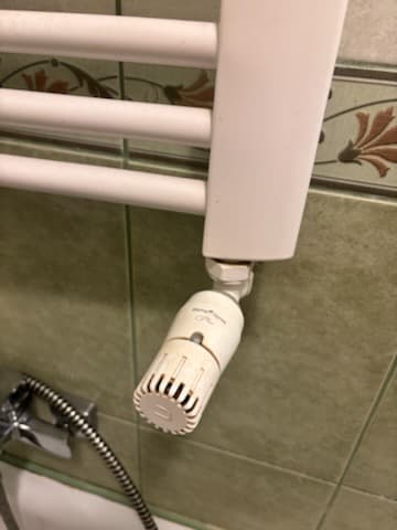 Zawór starego termostatu Zbliżenie na stary zawór termostatu przy grzejniku łazienkowym