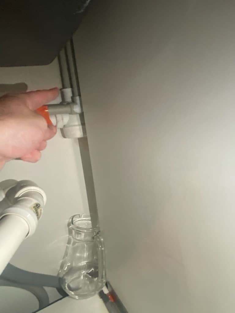 Miejsce nieszczelności pokazane przez hydraulika Hydraulik pokazujący miejsce nieszczelności na plastikowej rurce pod zlewem