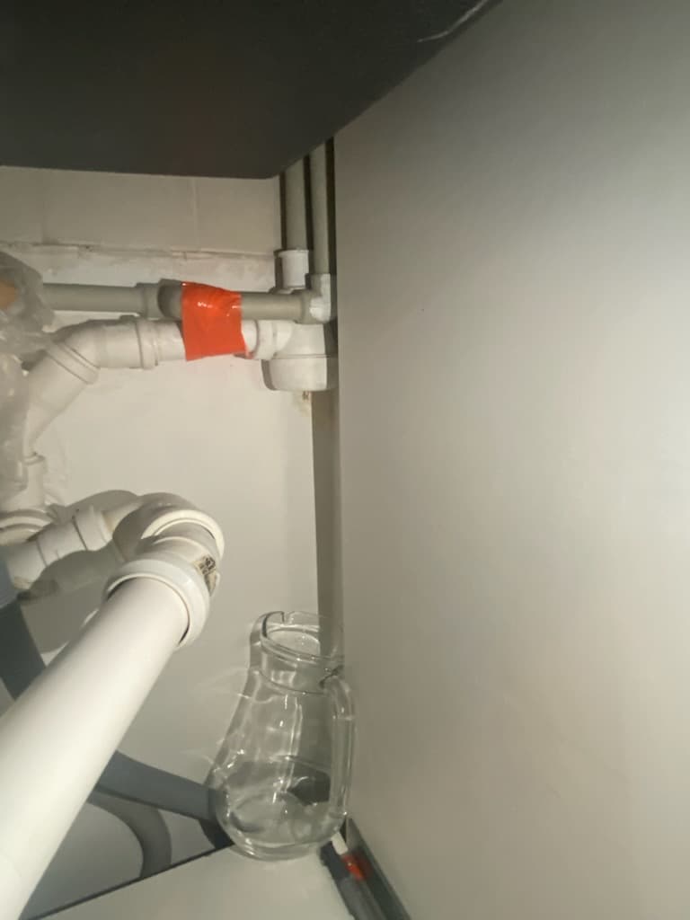 Uszkodzone kolanko rurki Zbliżenie uszkodzonego kolanka plastikowej rurki odpływowej pod zlewem