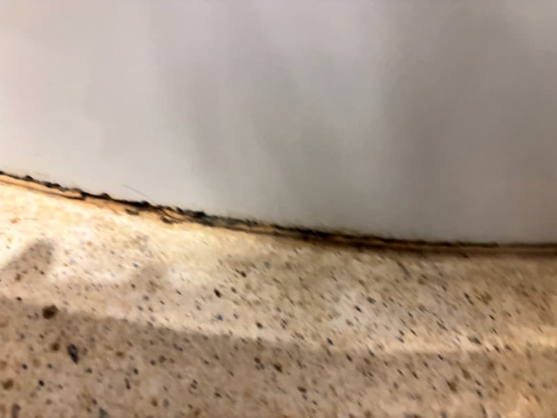 Stary silikon do wymiany Stary silikon przy podstawie ściany prysznica przed wymianą