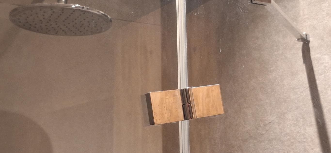 Zawias po naprawie Zbliżenie na zawias drzwi prysznicowych po dokonaniu regulacji