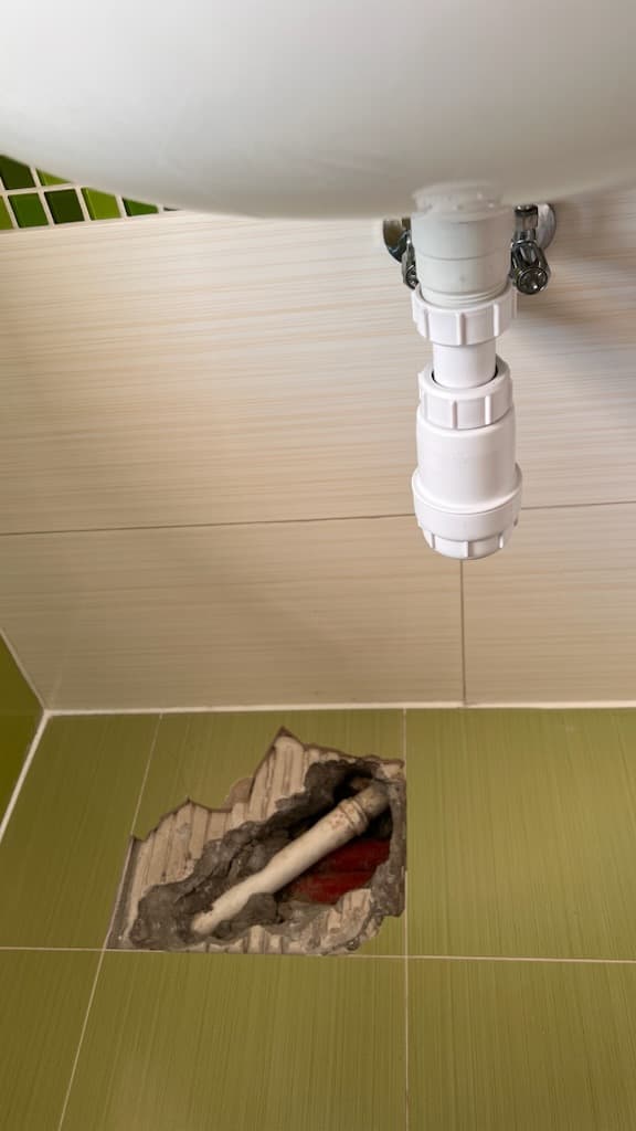 Nowy syfon pod umywalką Naprawiona sekcja ściany z nowym syfonem pod umywalką