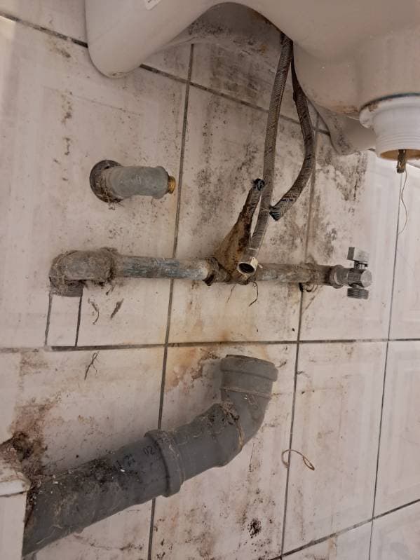 Demontaż rury odpływowej Demontowana stara rura odpływowa i zawory pod umywalką.