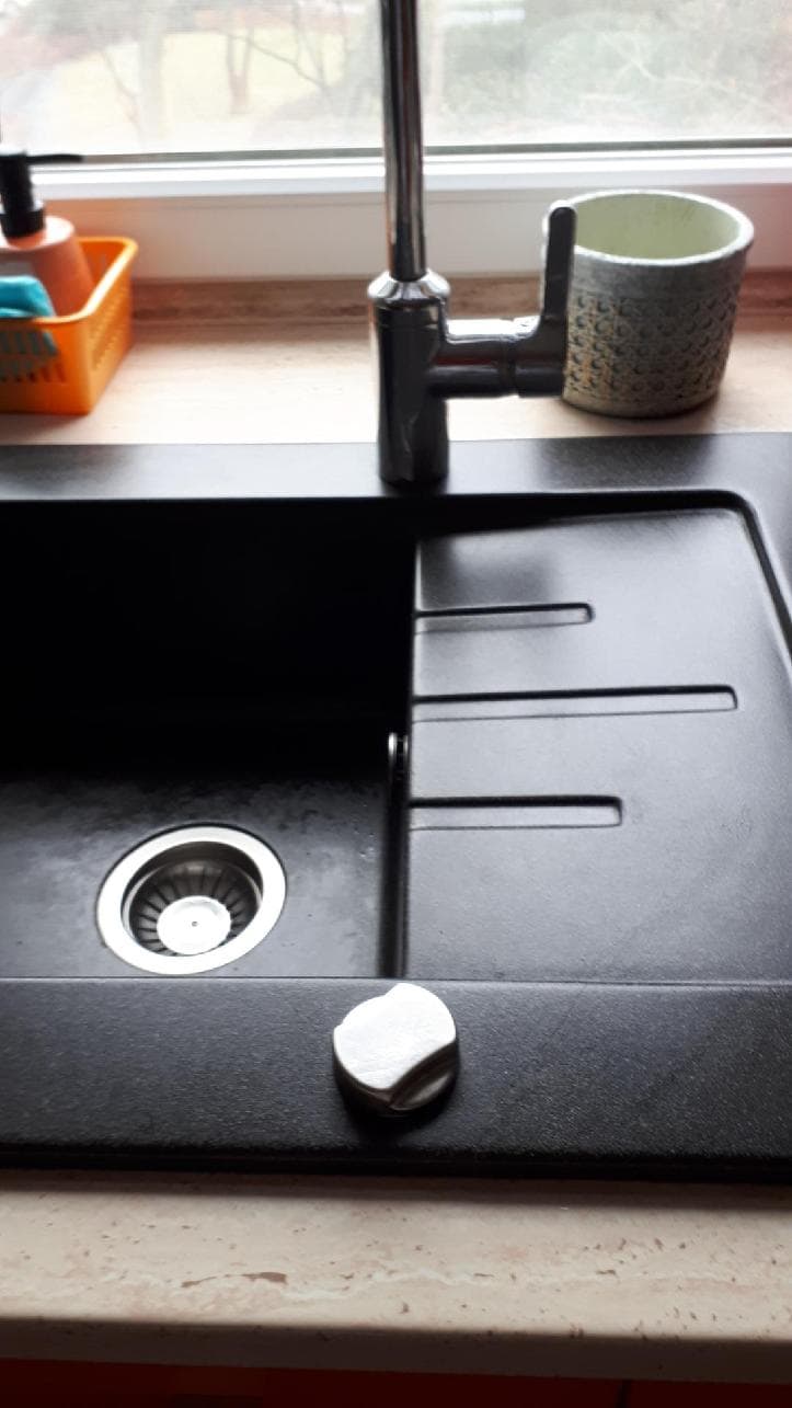 Detail kranu i ociekacza Detail kranu i części ociekowej nowego czarnego zlewu w kuchni