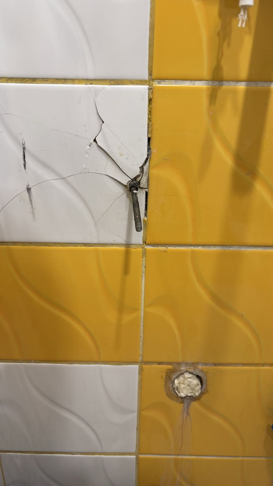 Pęknięta płytka przy kołku Pęknięta płytka ceramiczna przy uszkodzonym kołku