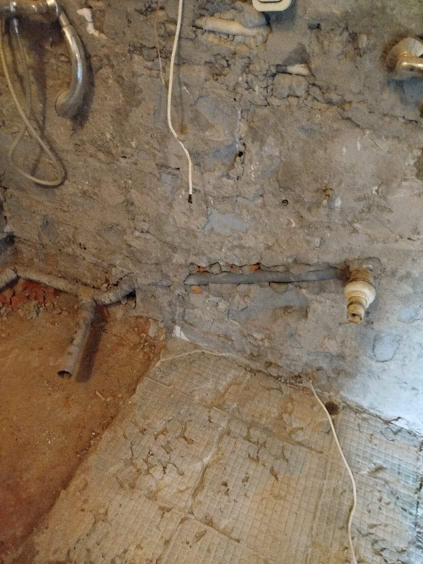 Ściana po wyburzeniu z instalacją wodną Ściana w łazience po wyburzeniu z widocznymi elementami instalacji wodnej