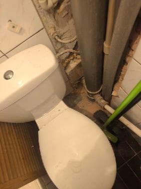 Stan przed modernizacją toalety Toaleta z widoczną rurą kanalizacyjną przy ścianie
